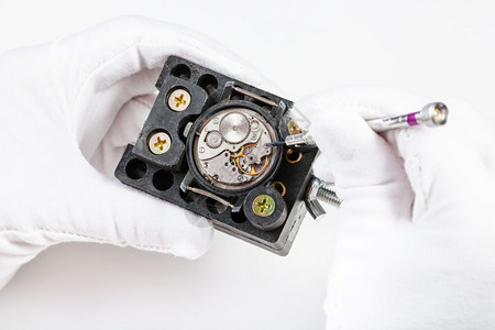 手表制作车间用白色背景的螺丝刀修理机械手表图片