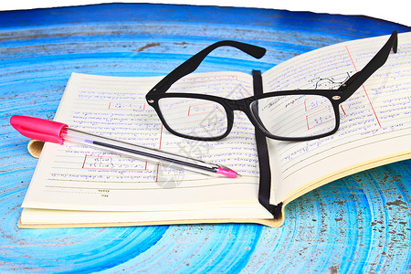 眼镜笔记本和放在桌上的功课图片