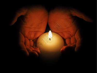 蜡烛和手放在黑色背景上背景图片