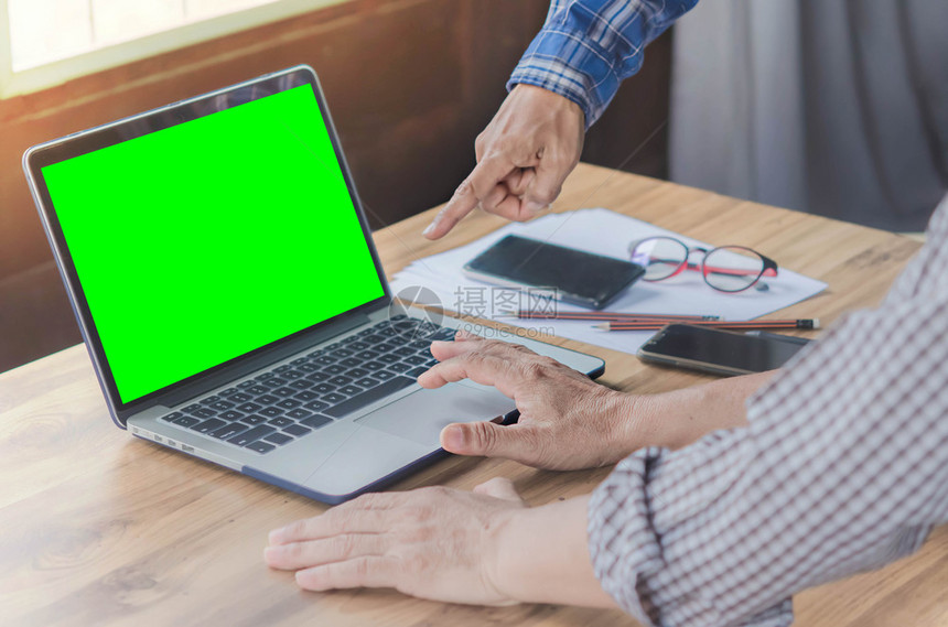 商人使用办公室绿色屏幕的手提笔记本电脑时髦语调在办公室工作的商人图片