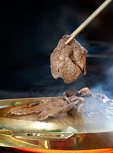 用筷子夹着的烤牛肉亚洲风格的热锅筷子夹烤牛肉图片