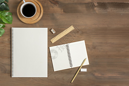 用空白笔记本品和咖啡杯平整的木制办公桌上面有空白的笔记本用品和咖啡杯图片