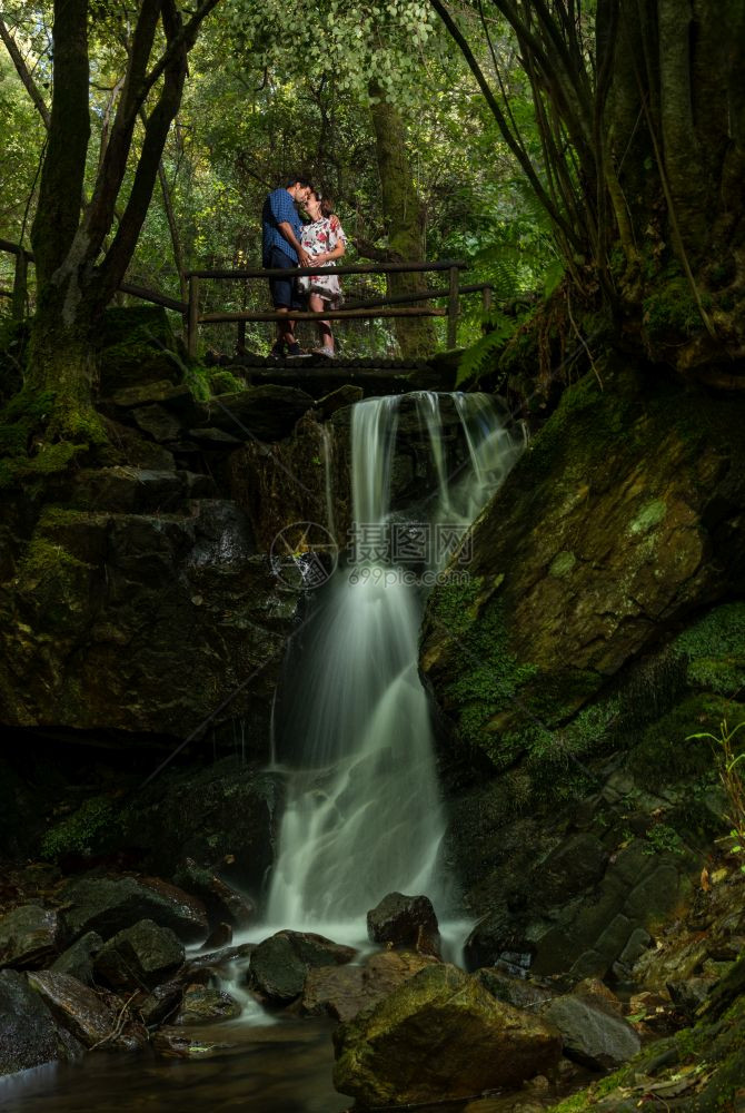 年轻夫妇在瀑布附近的自然双恋风景中享受孕期图片