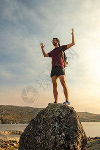 带着背包在山坡顶庆祝成功旅行的人在岩石山上积极享受健康的生活方式图片