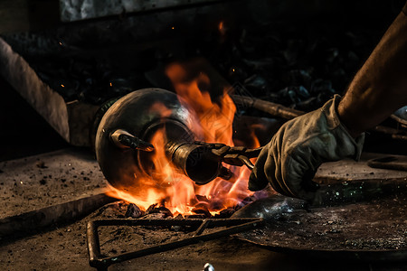 土耳其传统铁匠用火上喷洒的锡覆盖铜质物体背景图片