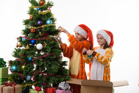 两个女孩装饰一棵圣诞树孤立在白色背景上图片