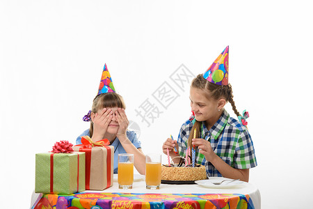 一个女孩用手遮住眼睛另一个插在生日蛋糕里图片
