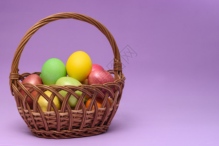 紫色背景的篮子里装满了彩色的蛋背景图片