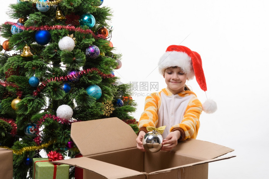 一个女孩装饰圣诞树从盒子里拿出圣诞玩具图片
