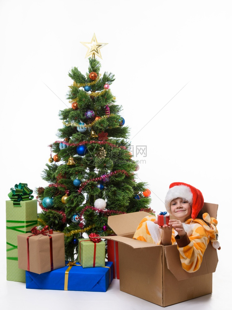 带着小礼物的女孩坐在圣诞树附近的一个病箱里图片