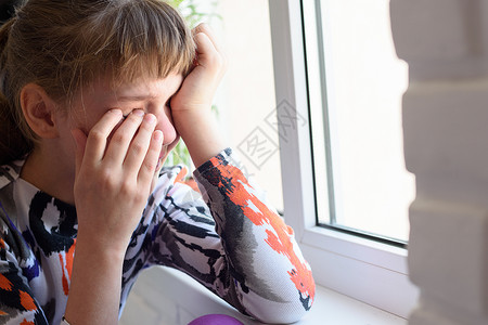 离家出走的女孩在窗边痛苦地哭泣图片