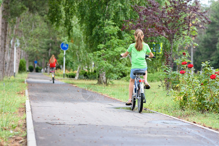 女孩骑在城市公园的特殊自行车路上图片
