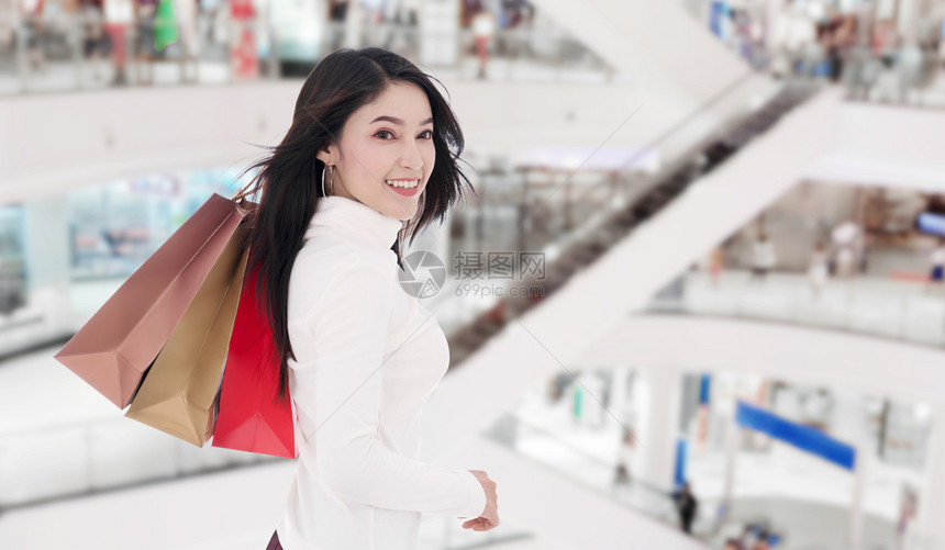 快乐的年轻女子在商场拿着购物袋图片
