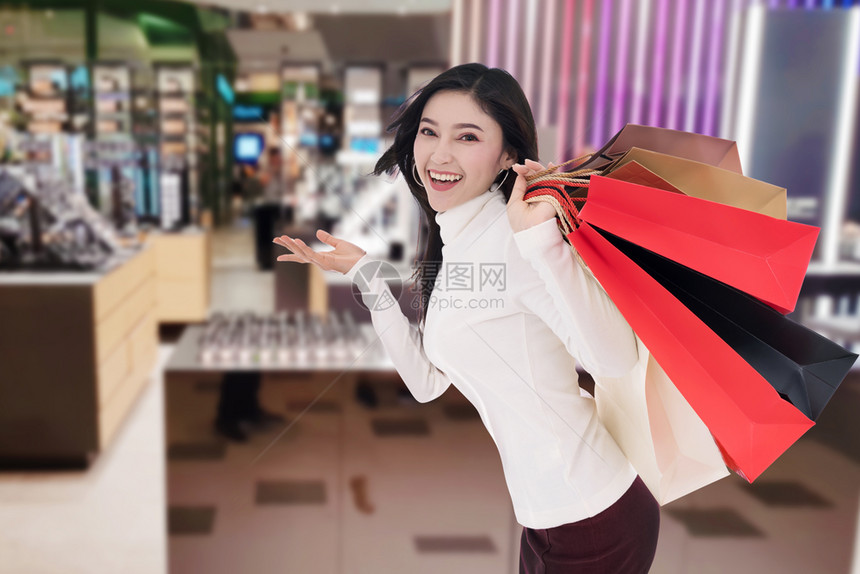开心的年轻女子在商场拿着购物袋图片