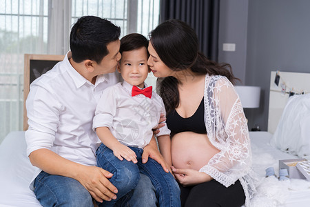 幸福家庭概念怀孕母亲和父在床上吻男孩图片