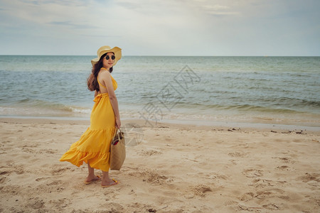 穿着黄色衣服的女人站在海边风吹的图片