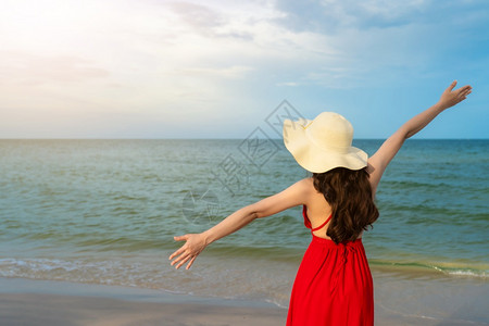 身着红裙子的自由妇女手举在海边的图片