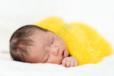 新生儿睡在床上的黄色毛毯里图片