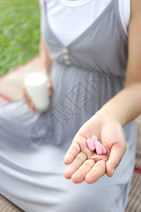 孕妇手里有一杯牛奶和维生素药丸图片