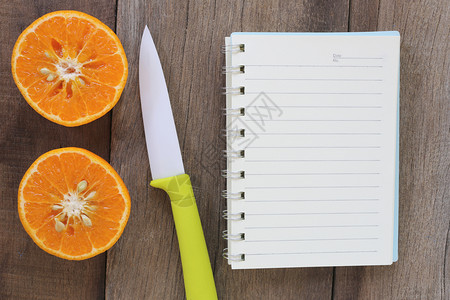 放在旧木制地板上的普通橘子和丙烯刀设计关于健康食品的概念背景图片