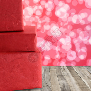 红礼盒堆在木地板上红色的bokeh抽象背景背景图片