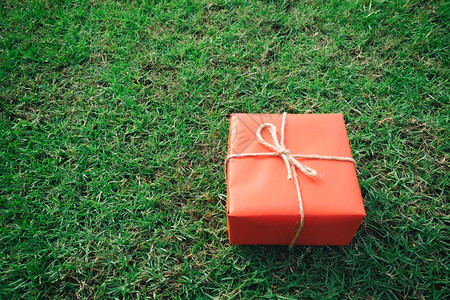 圣诞新年情人节或周纪念日绿草坪上的红礼盒背景图片