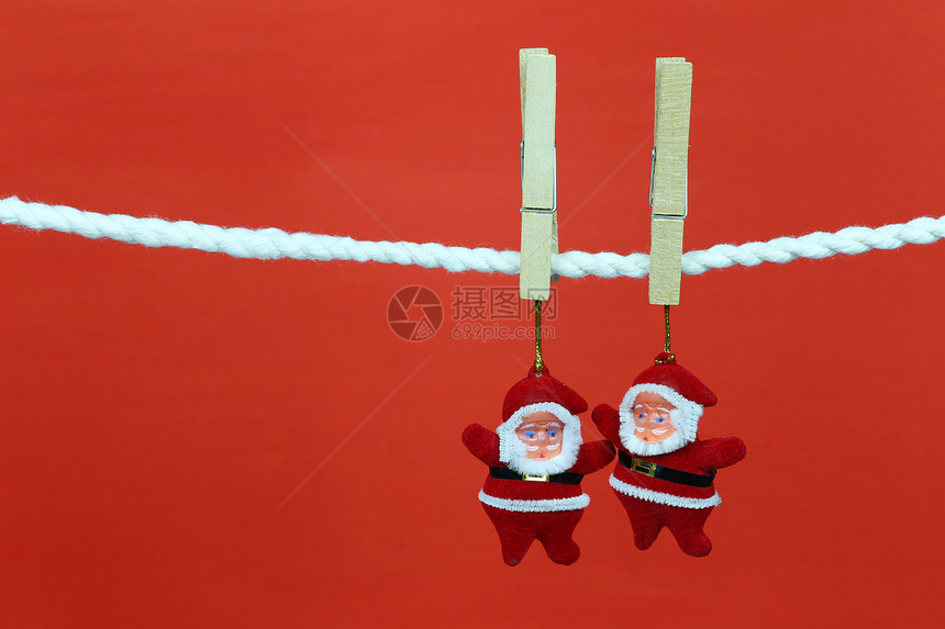 圣诞老人娃挂在衣绳上并有复制空间红色背景设计你的工作概念图片