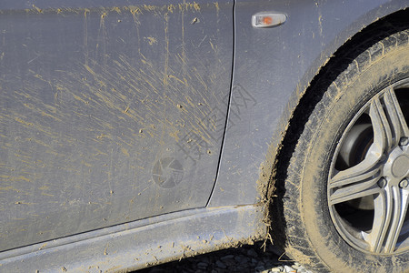 混泥土车车轮挡泥板和门上的土结果是穿过泥土肮脏的汽车轮椅挡泥板和车门上的土结果是穿过泥土背景