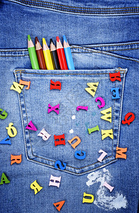 英文字母的多彩木散在蓝色牛仔裤上用一个袖口铅笔整框图片