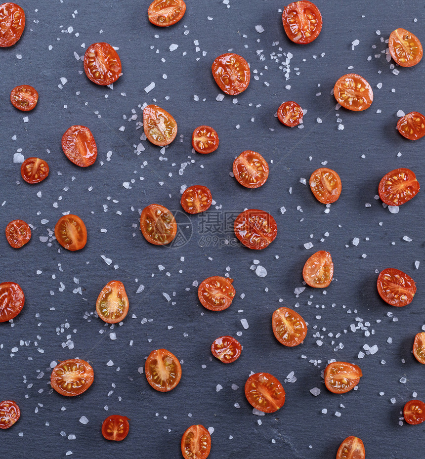 半熟的红樱桃番茄洒满黑底的盐图片