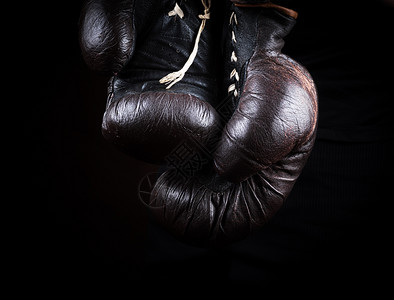 一对非常古老的棕色拳击手套挂上黑色背景图片