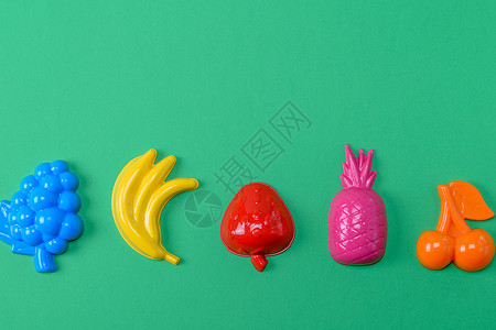 卡通水果香蕉多色塑料玩具水果绿色背景复制空间背景