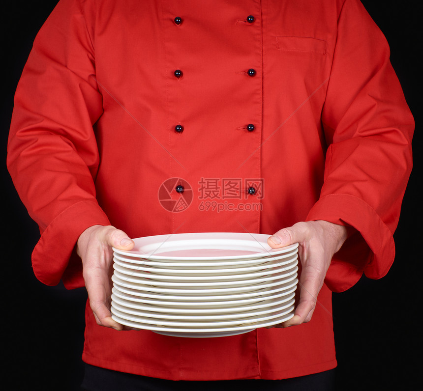 身穿红衣厨服的师手里握着一堆圆白空盘子黑底图片