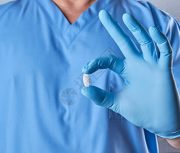 戴白药片的蓝色乳胶手套医生身着白药片穿制服的男子图片