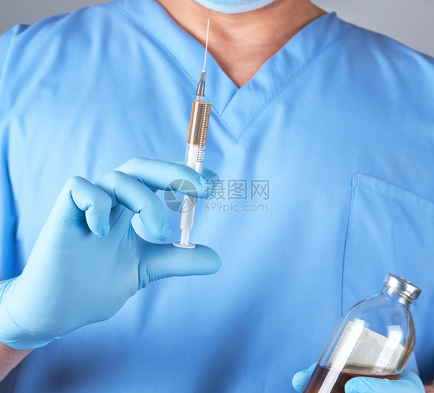 穿蓝制服的男医生拿着注射用红色液体的针筒关上图片