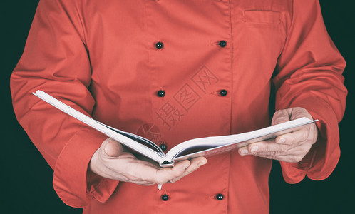 穿着红制服的厨师持有开放式笔记纸黑色背景图片