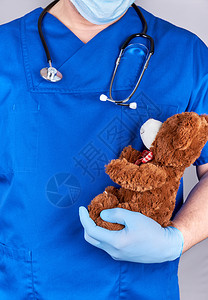 蓝制服医生和戴棕色泰迪熊儿科医生的旧乳胶手套图片