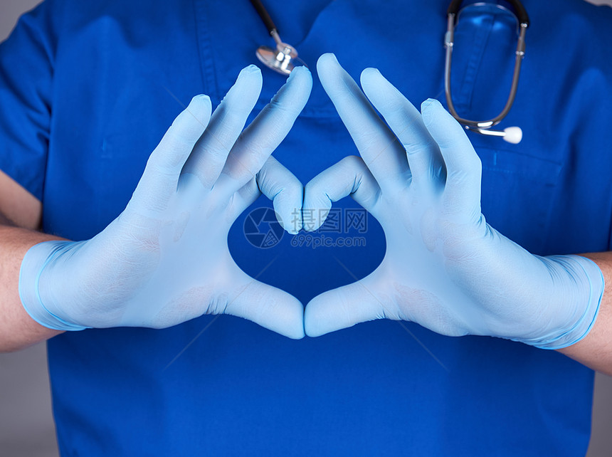 穿蓝色制服和旧乳胶手套的医生显示心脏手势关上图片