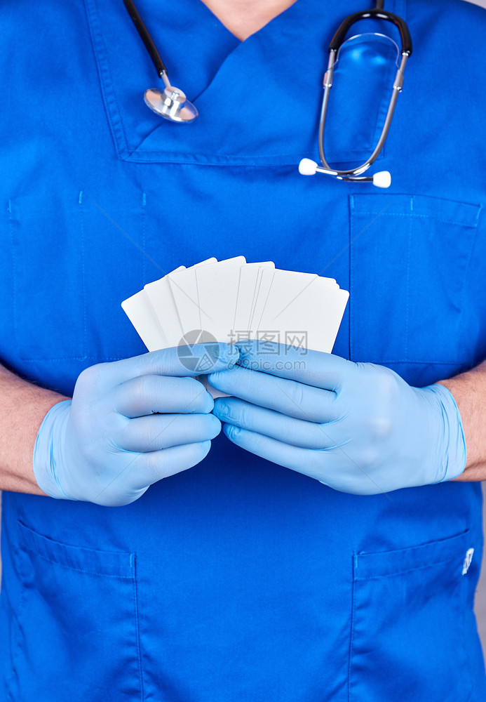 穿着蓝色乳胶手套的男医生持有空白纸名片关闭图片