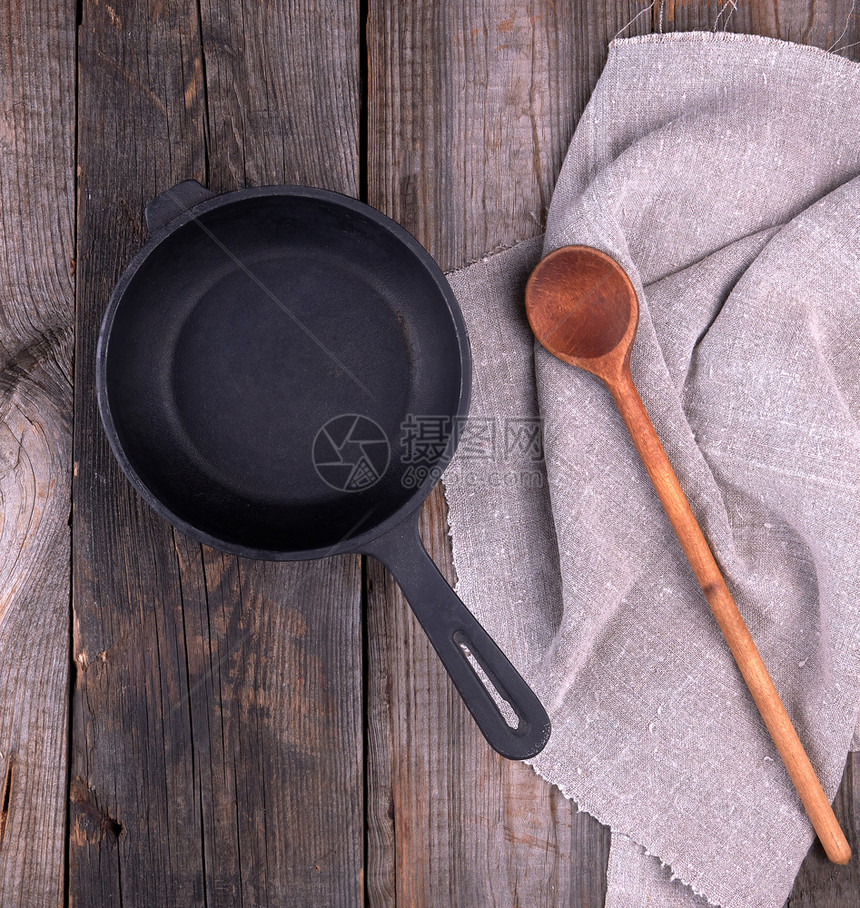 黑色圆煎锅手柄和勺子放在木桌顶视图上图片