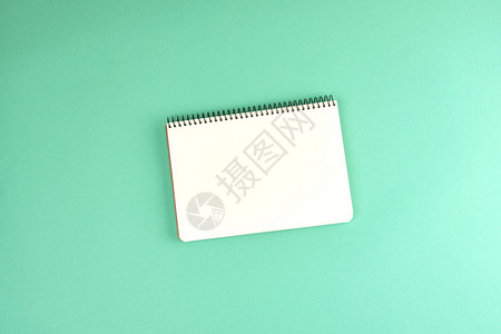 开张螺旋笔记本在绿色背景顶视图上用干净白纸打开笔记本背景图片