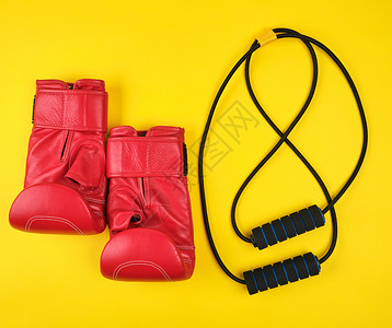 一对红色皮衣拳击手套和黑色教练推黄色平面图片
