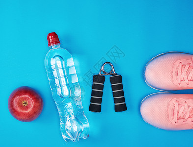 蓝色背景的塑料水瓶红成熟苹果和运动推广器背景图片