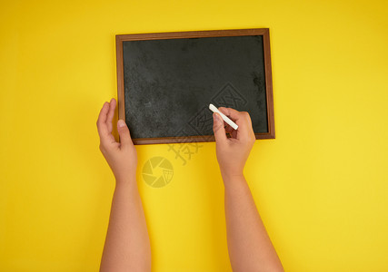 黑白粉笔架和两只手与一块黄色白粉笔图片