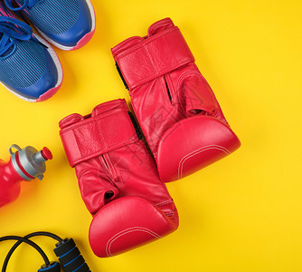 红色拳击手套和蓝运动鞋顶视黄色背景平底图片