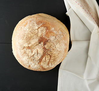 在毛巾上烤圆白小麦面包木制旧桌黑色背景图片