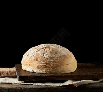 在毛巾上烤圆白小麦面包木制旧桌黑色背景图片