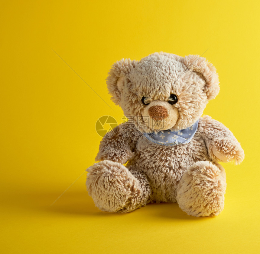 棕色泰迪熊坐在黄背景上图片