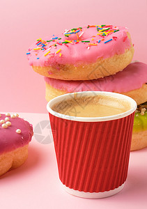 红色圆面甜圈和纸杯粉红背景的咖啡关闭图片