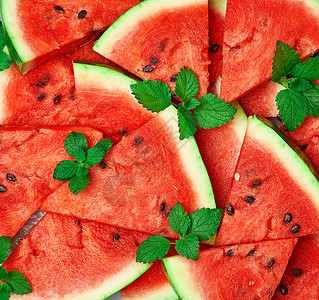 切片三边熟的红西瓜片种子配绿色薄荷叶明亮的夏季纹理背景背景图片